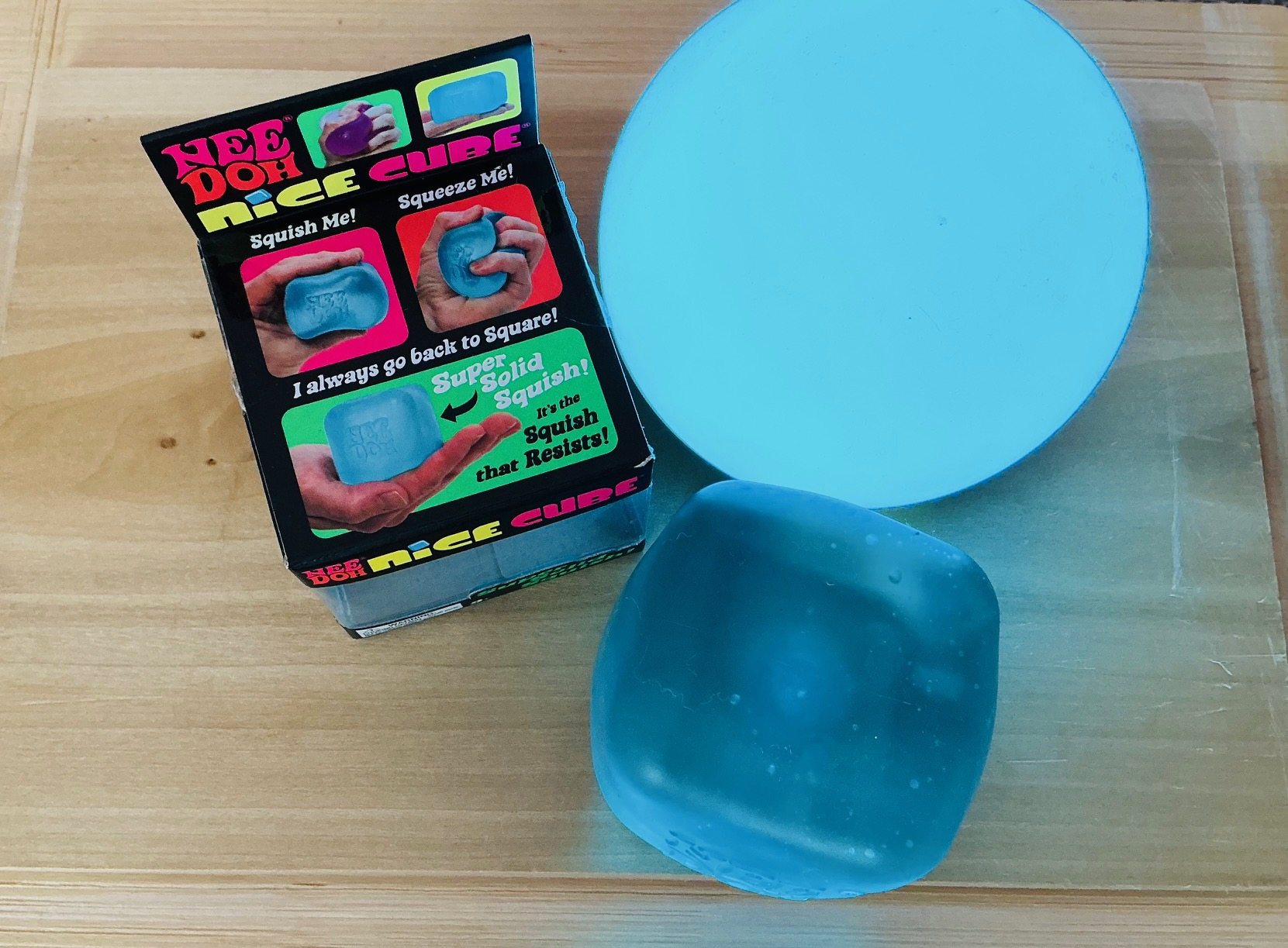 Andrew Rider's original photograph of a blue NeeDoh Nice Cube being compressed beside its package